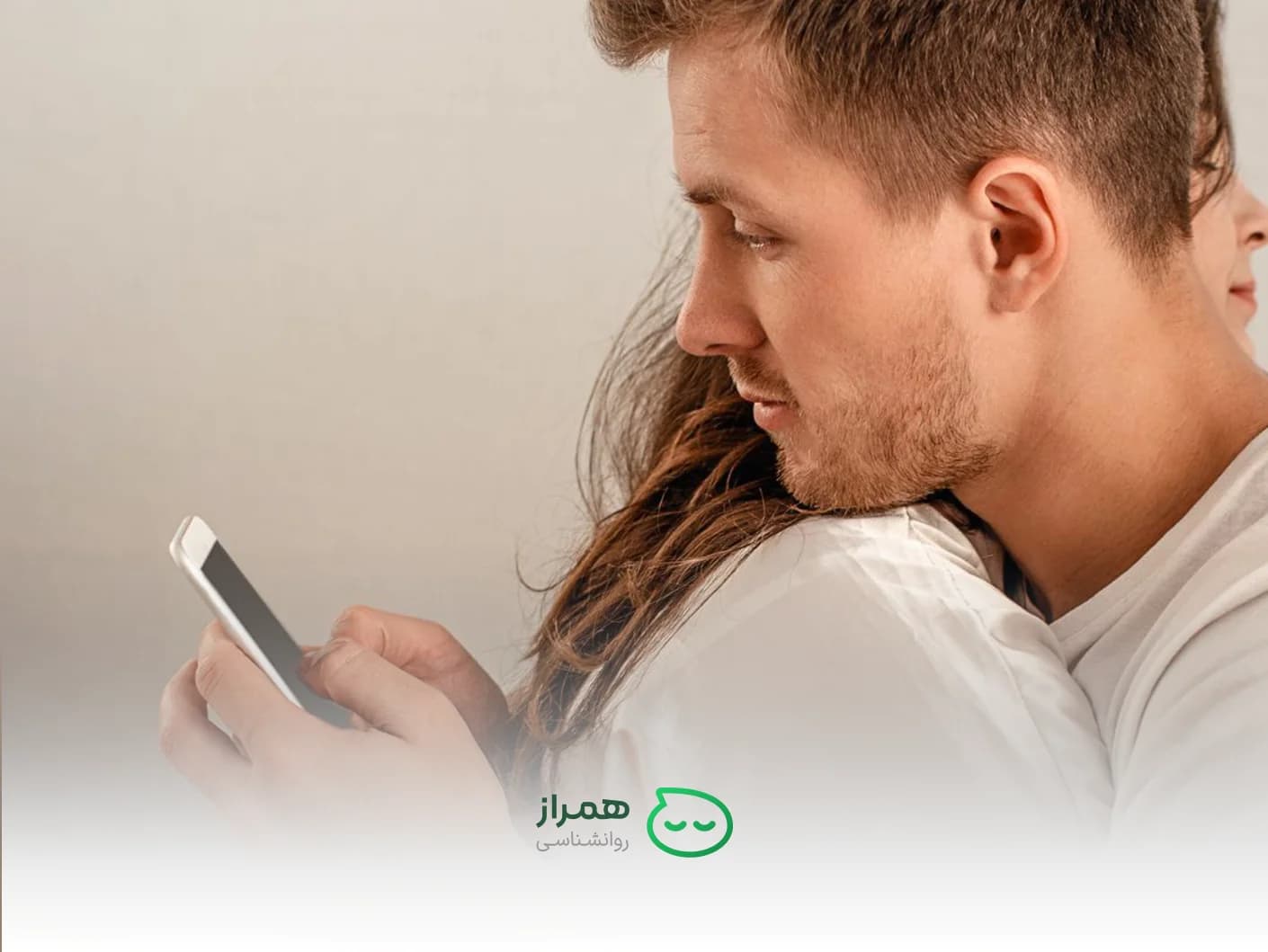 Man secretly looking at phone while hugging his partner – sign of emotional distance and possible infidelity